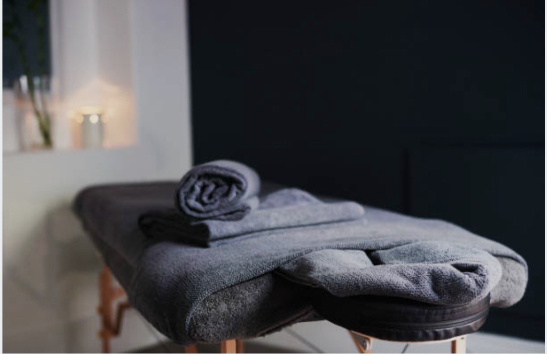 Professional massage table with dark towels and ambient candlelight