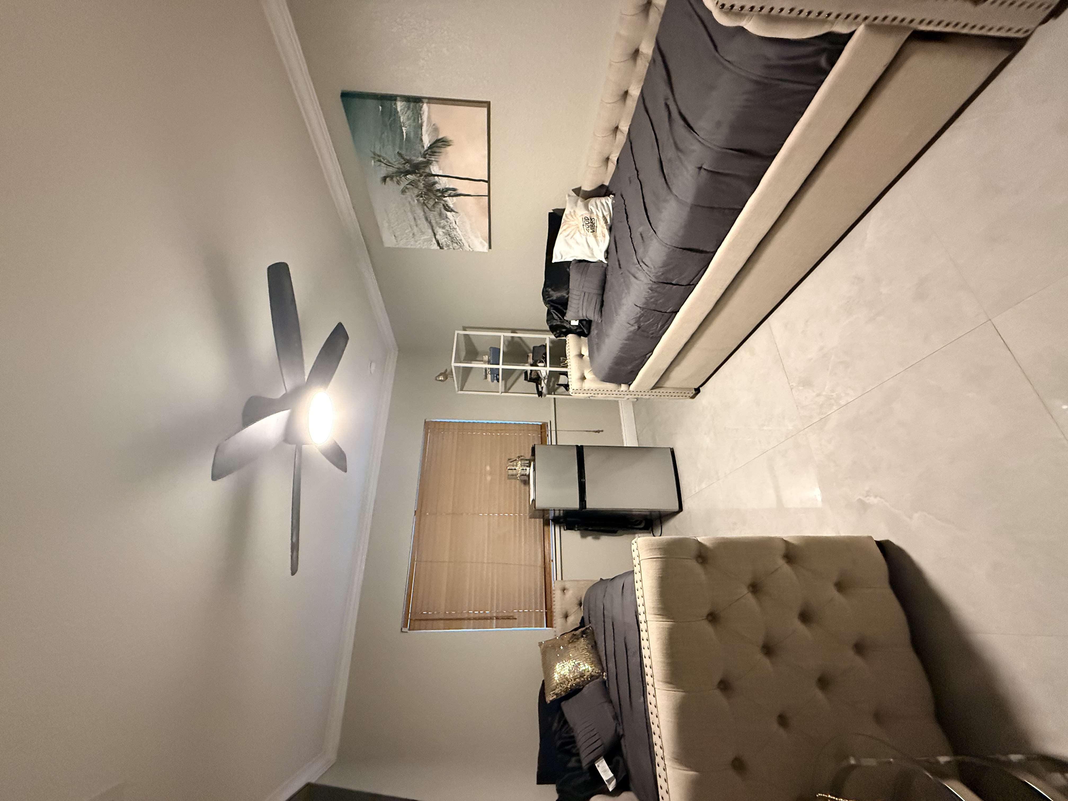 Private recovery suite bedroom with tufted headboard, ceiling fan, and beach art